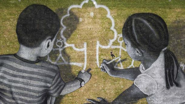 Artist Saype poses with his land art painting at UN Headquarters, Geneva, Switzerland (© Valentin Flauraud/EPA-EFE/Shutterstock)