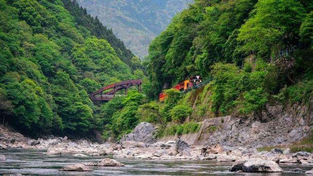 Ein Zug fährt entlang des Hozugawa-Flusses in Arashiyama, Kyoto, Japan (© Alvin Huang/Getty Images)