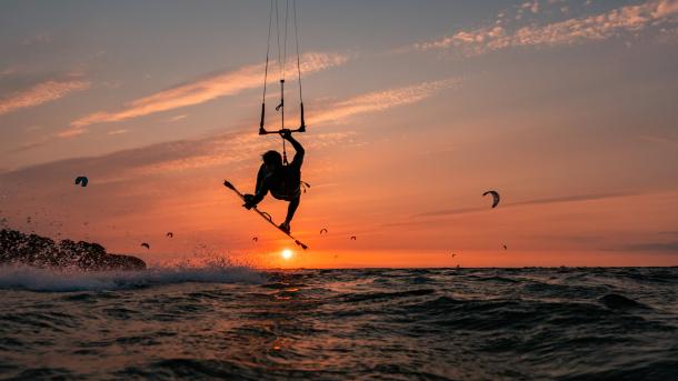 Silhouette eines springenden Kitesurfers bei Sonnenuntergang im baltischen Meer (© Jens Breuer/Getty Images)