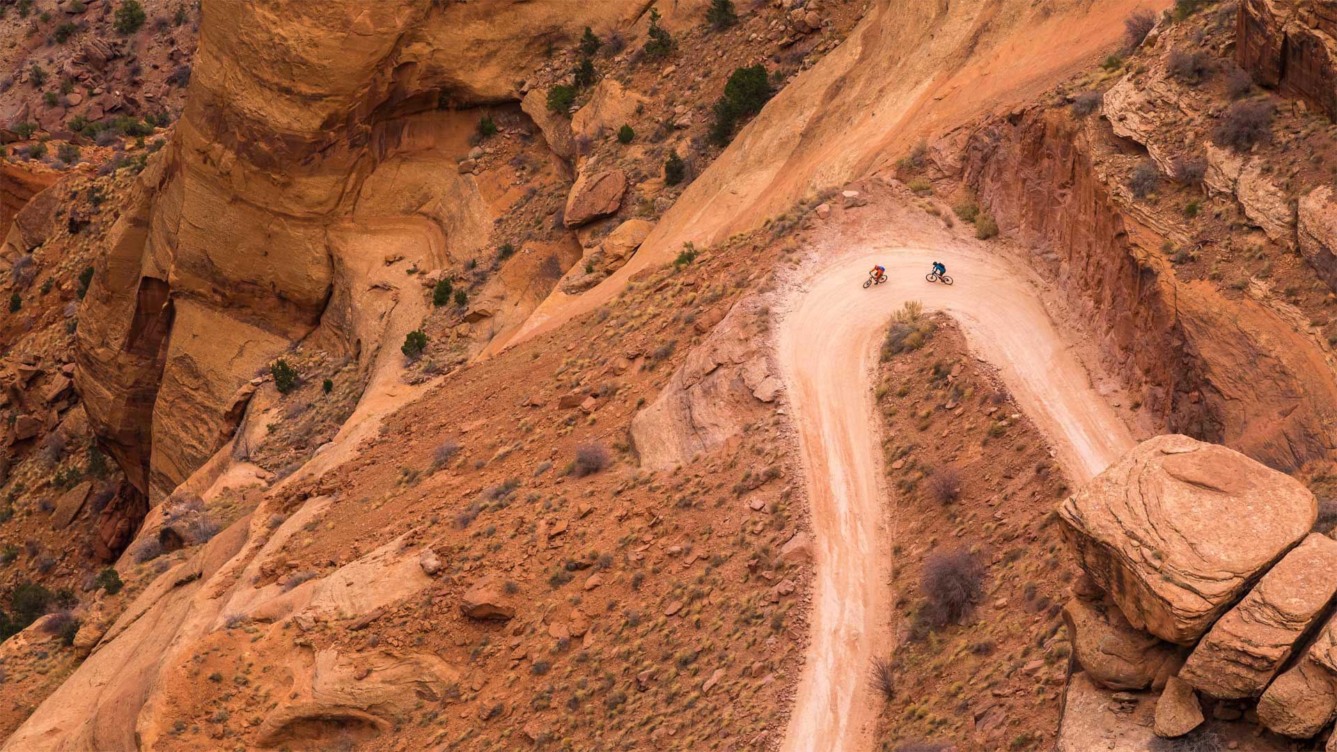 两名山地车骑手在白缘公路上沿着谢福小道的转弯处骑行 ，犹他州峡谷地国家公园 