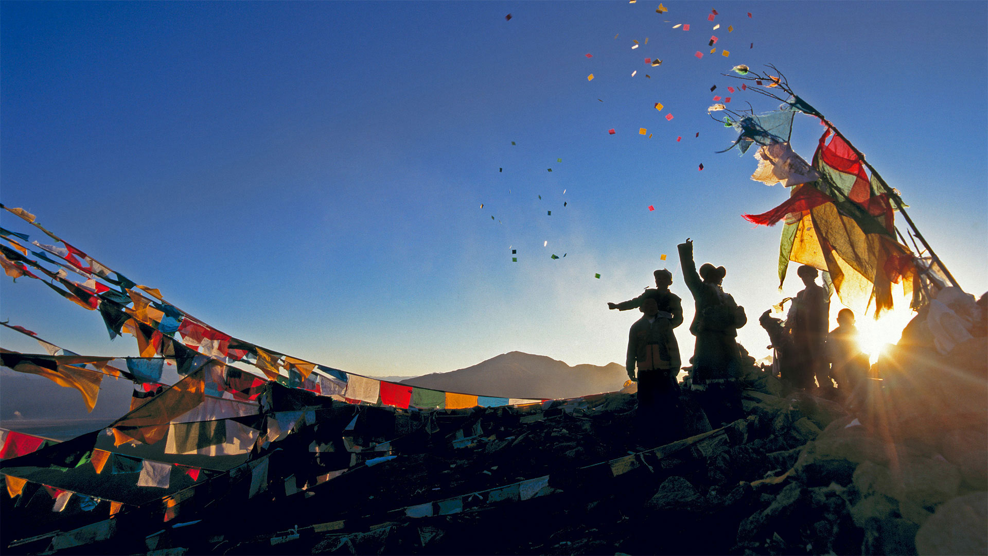 朝圣者将风马旗扔向甘登寺上方的空中为新年祈福，中国西藏 